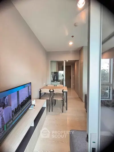 Modern living room with sleek furniture and large TV in a stylish apartment.