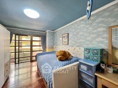 Cozy bedroom with hardwood floors, whimsical sky-themed wallpaper, and direct balcony access, perfect for comfortable living.