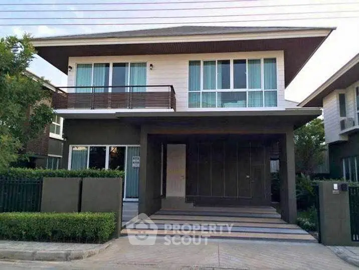 Modern two-story house with large windows and balcony in a serene neighborhood.