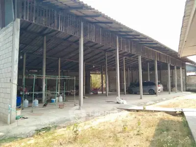 Spacious open-air storage area with partial roofing and parked car, ideal for versatile use.