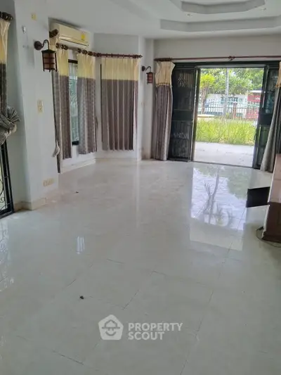 Spacious living room with large windows and garden view, perfect for natural light lovers.