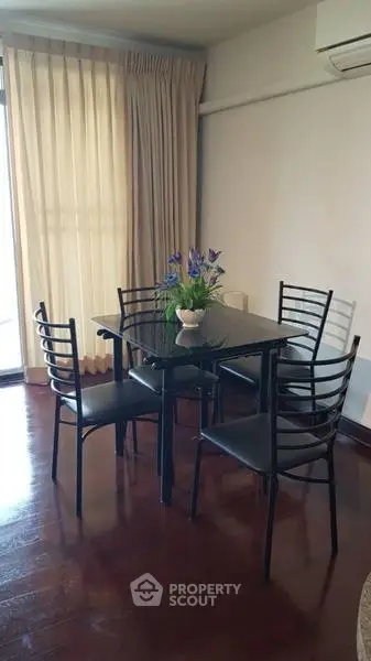 Charming dining area with elegant black table and chairs, complemented by a floral centerpiece and natural light.
