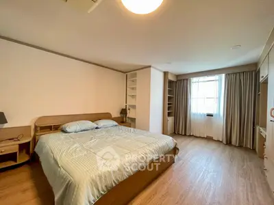 Spacious bedroom with wooden flooring and large window for natural light