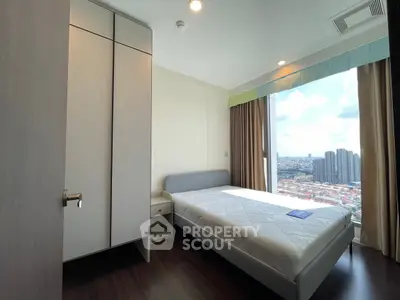 Modern bedroom with city view, featuring sleek furniture and large window for natural light.