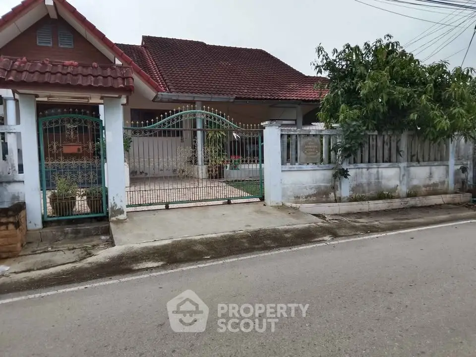 Charming suburban house with gated entrance and red-tiled roof, perfect for family living.