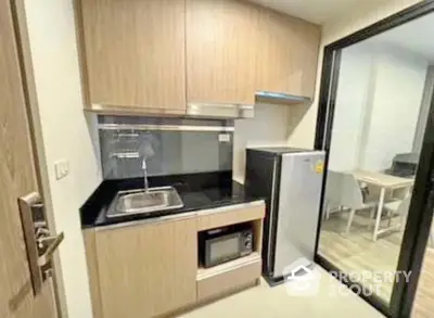 Modern compact kitchen with wooden cabinets and black countertop in a stylish apartment.