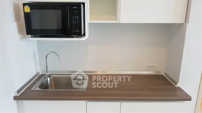 Modern kitchen with sleek countertop and built-in microwave, perfect for urban living.