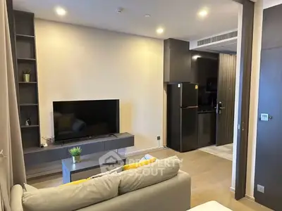 Modern living room with sleek design and integrated kitchen, featuring a large TV and stylish decor.