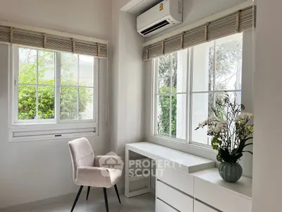 Bright study room with modern decor and large windows overlooking greenery.