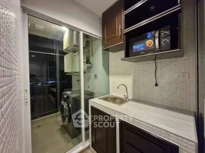 Modern kitchen with sleek cabinetry and built-in appliances, featuring a washing machine and microwave.