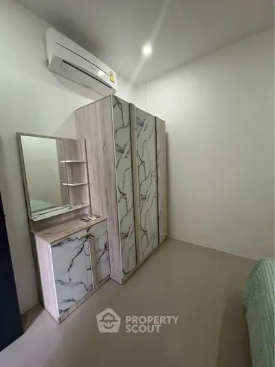Modern bedroom with sleek marble-patterned wardrobe and air conditioning unit.