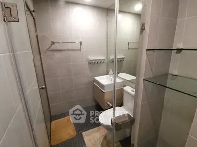 Modern bathroom with sleek fixtures and glass shower enclosure in contemporary apartment.