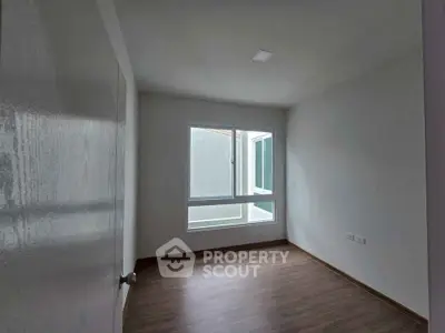 Spacious empty room with large window and wooden flooring, perfect for customization.