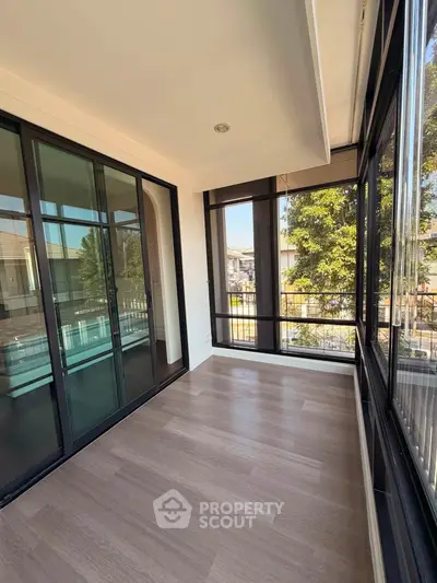 Spacious sunlit balcony with large glass doors and scenic view, perfect for relaxation and enjoying the outdoors.