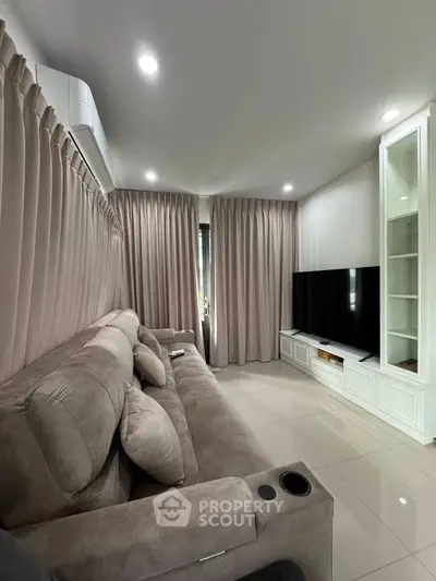 Cozy living room with plush sofa and large TV, perfect for relaxation.