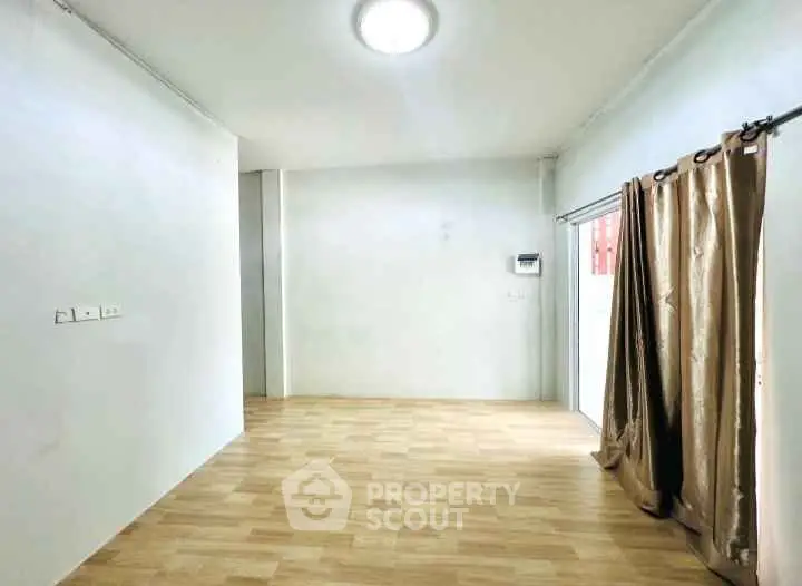 Spacious empty room with wooden flooring and natural light, ideal for customization.