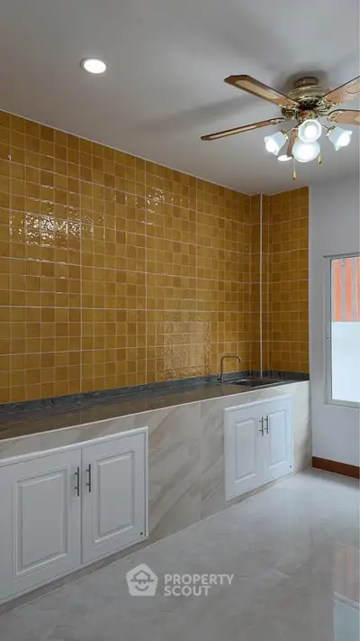 Modern kitchen with yellow tiled backsplash and ceiling fan