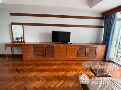 Spacious living room with polished parquet flooring, classic wooden TV console, and large windows draped in blue curtains.