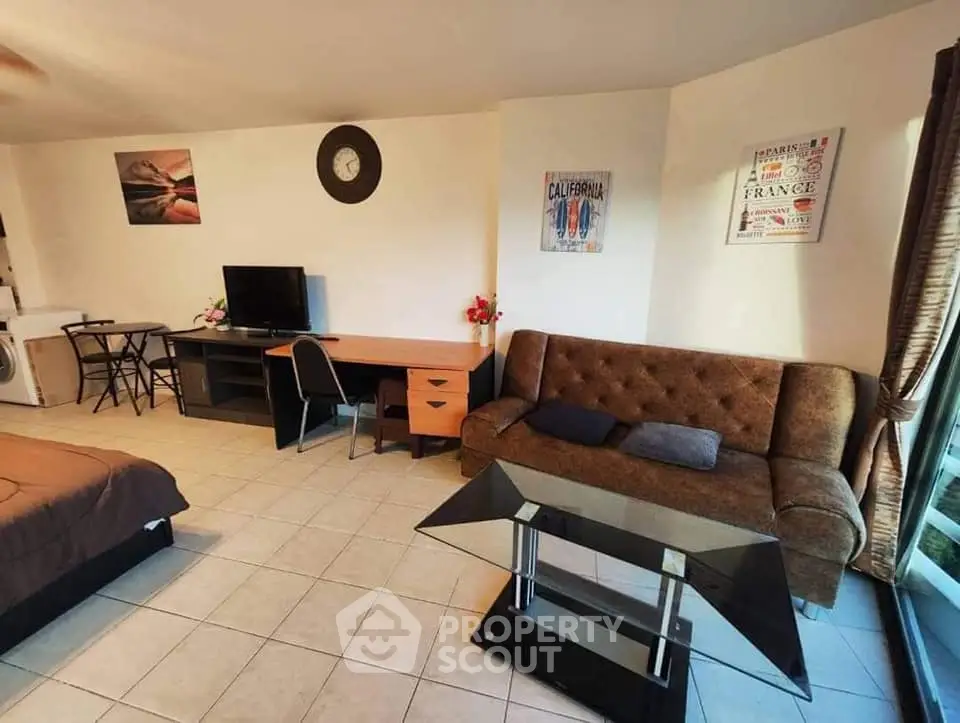 Spacious living room with modern decor and natural light, featuring a cozy sofa and stylish glass table.