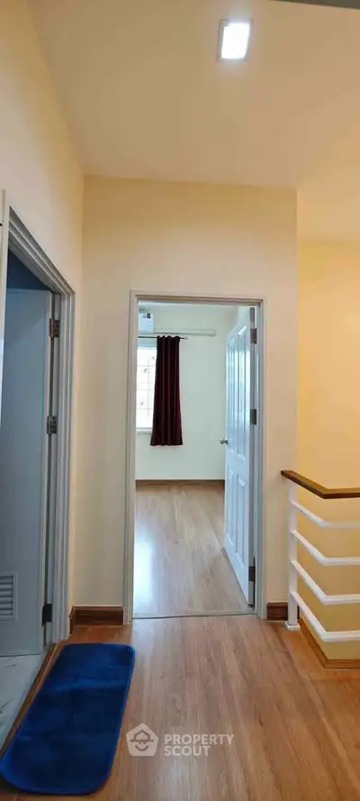 Spacious hallway leading to a bright bedroom with wooden flooring and modern design.