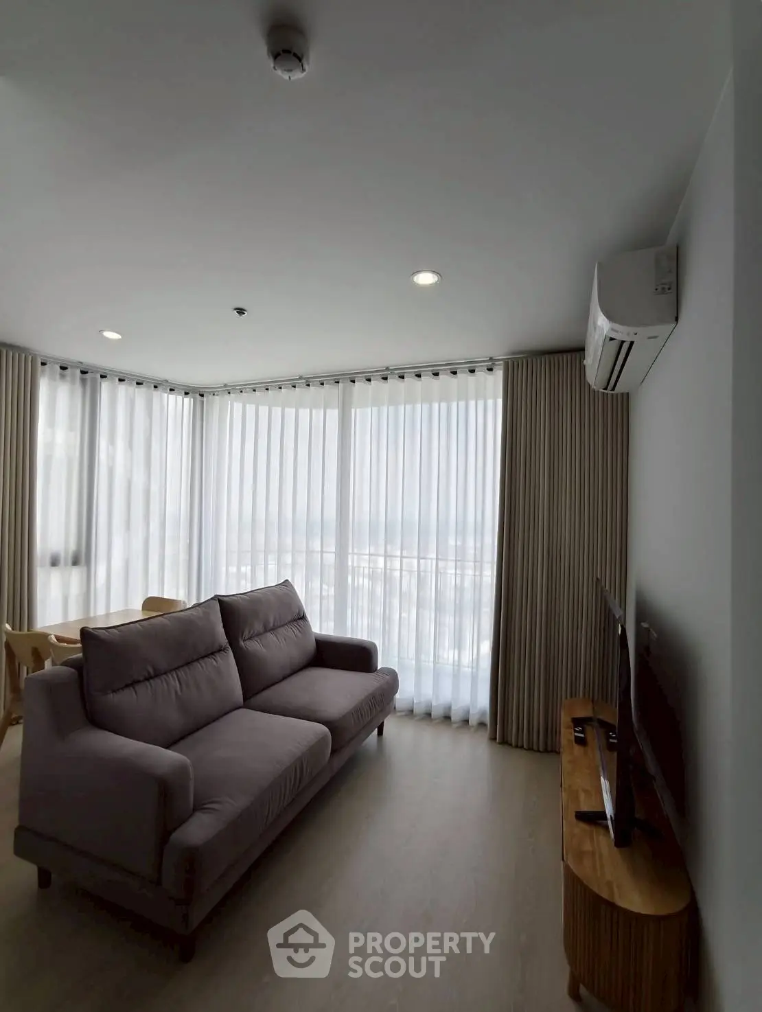 Modern living room with large windows and stylish furniture in a high-rise apartment.