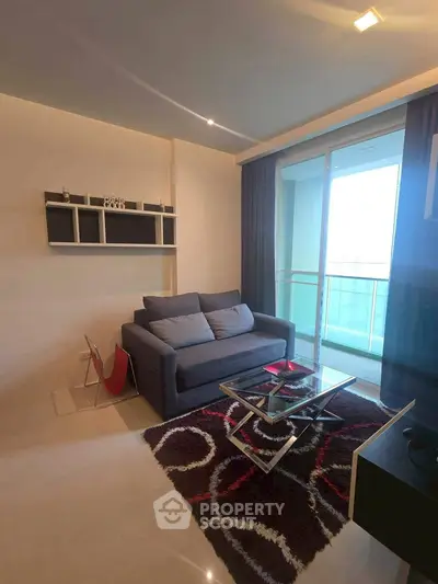 Modern living room with stylish sofa and glass coffee table, featuring a balcony view.