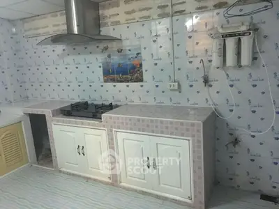 Simple kitchen with gas stove and tiled countertops in a modest home setting.