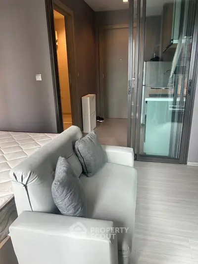 Modern studio apartment with compact kitchen and cozy seating area, ideal for urban living.
