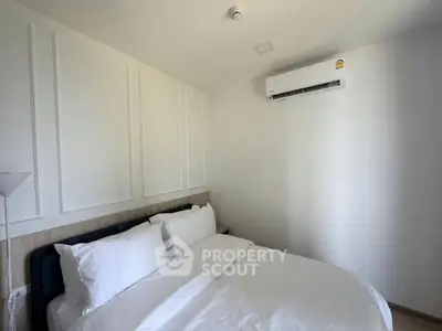Modern bedroom with white walls, cozy bed, and air conditioning unit.