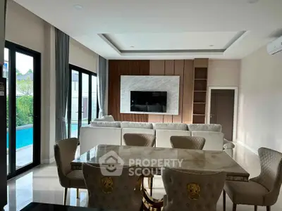 Luxurious living room with elegant dining area and pool view, featuring modern decor and ample natural light.