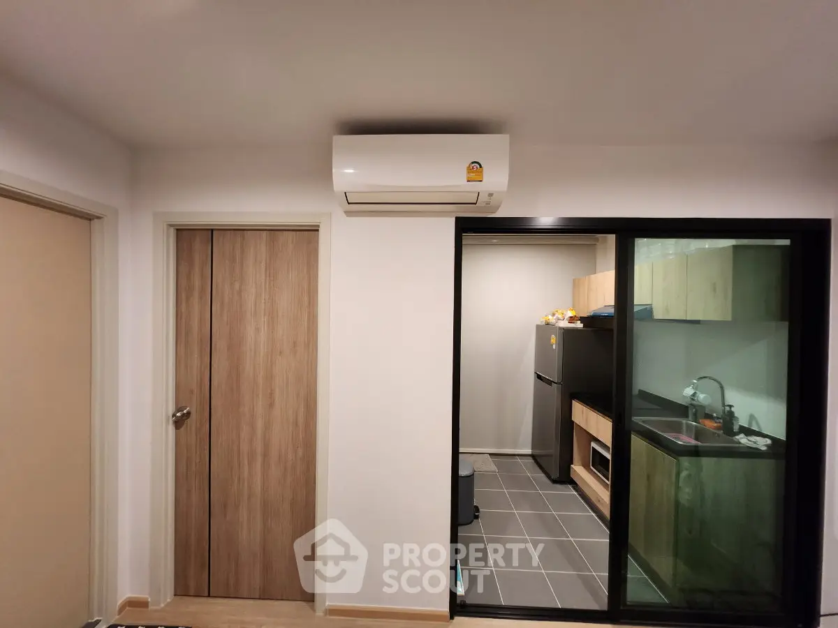 Modern apartment interior with sleek kitchen and air conditioning unit, showcasing contemporary design and functionality.
