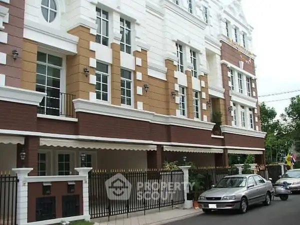 Elegant multi-story residential building with classic facade and parked cars.