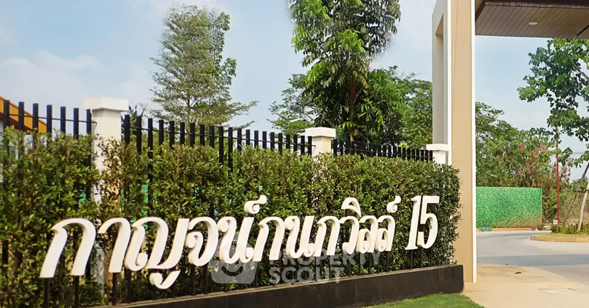 Charming entrance of residential property with lush greenery and welcoming sign.