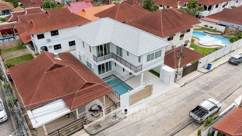 Stunning aerial view of a modern house with pool in a vibrant neighborhood.