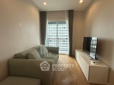 Modern living room with cozy sofa and large TV, featuring a balcony view in a high-rise apartment.