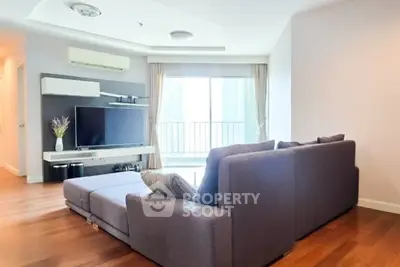 Spacious living room with modern decor and large window leading to balcony.