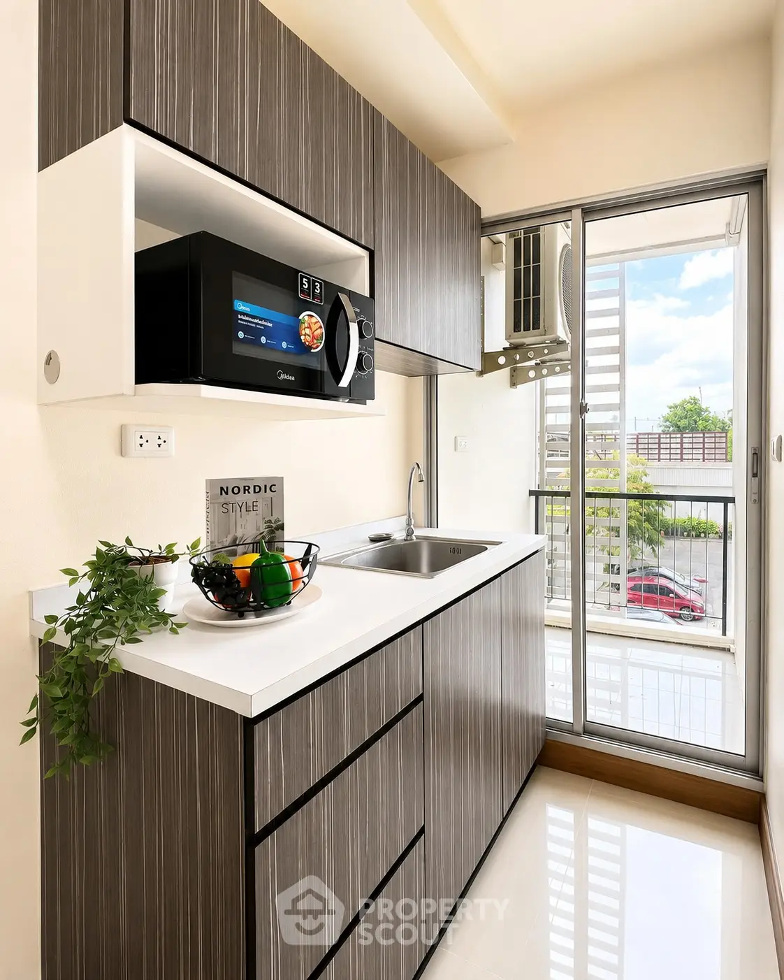 Modern kitchen with sleek cabinetry and balcony access, featuring a built-in microwave and stylish decor.