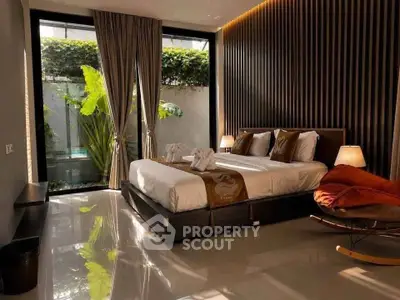 Luxurious bedroom with modern decor and large window overlooking lush greenery.