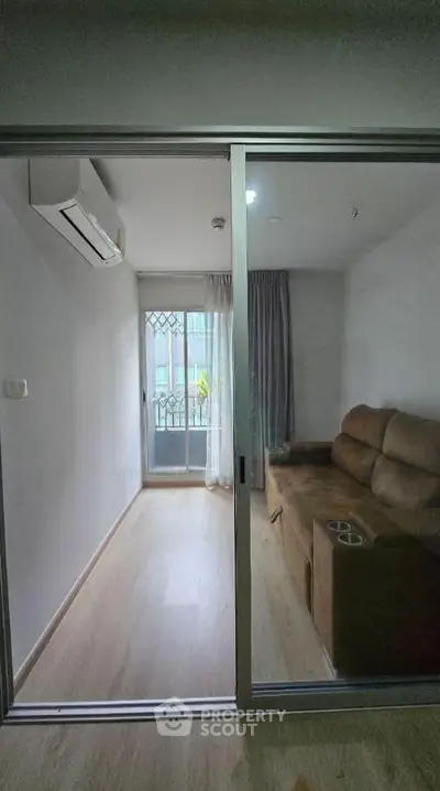 Cozy living room with sliding glass door and air conditioning, featuring a comfortable brown sofa.