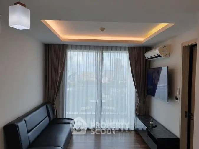Modern living room with sleek furniture and large window offering natural light.