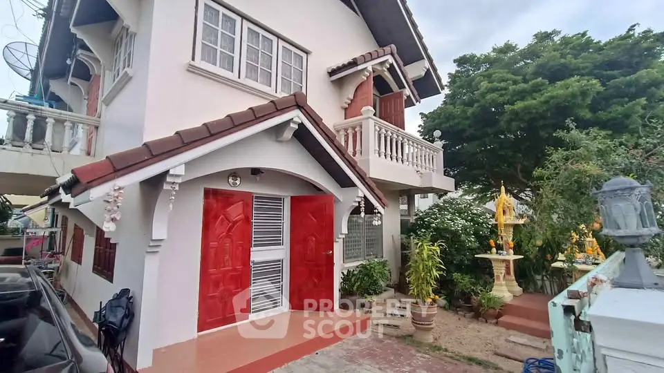 Charming two-story house with red doors and lush garden, perfect for family living.