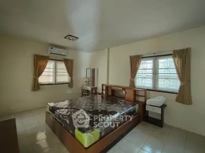 Spacious bedroom with large windows and modern furnishings in a cozy apartment.