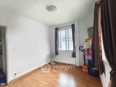 Spacious empty room with wooden flooring and large window, ideal for customization.