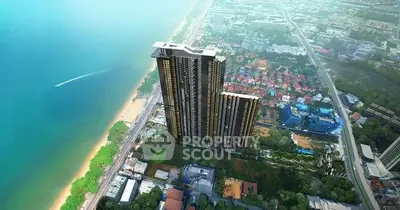 Stunning aerial view of a modern high-rise building near the beach with lush surroundings.