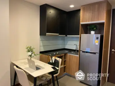 Modern kitchen with sleek design, featuring stainless steel fridge and cozy dining area.