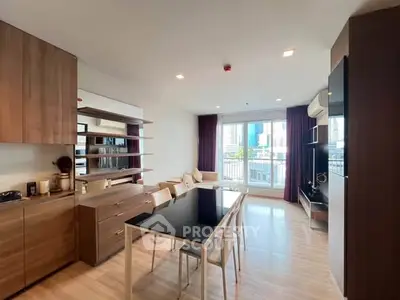 Modern open-plan living room with dining area and city view balcony in a stylish apartment.