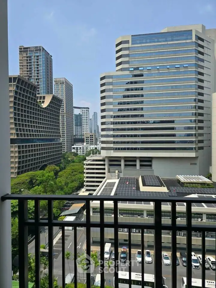 Stunning cityscape view from a modern balcony overlooking high-rise buildings and lush greenery.