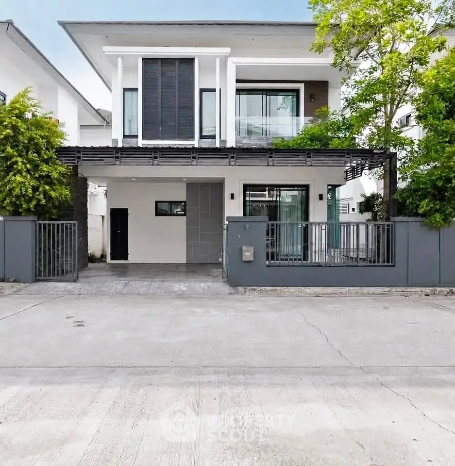 Modern two-story house with sleek design and lush greenery in a serene neighborhood.