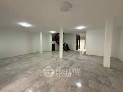 Spacious open-plan interior with tiled flooring and staircase, ideal for versatile living space.