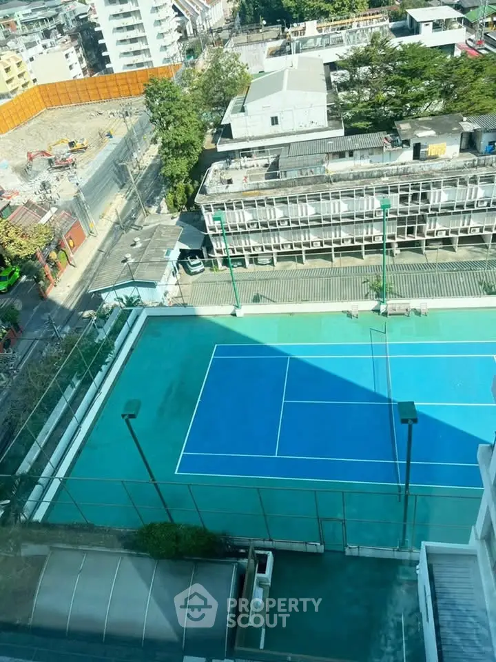 Stunning aerial view of urban tennis court surrounded by cityscape, perfect for sports enthusiasts.